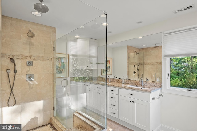 bathroom featuring double vanity, visible vents, tile patterned flooring, a stall shower, and a sink