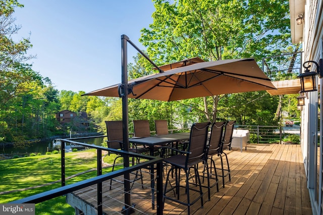 wooden deck featuring a lawn, outdoor dining area, and a water view