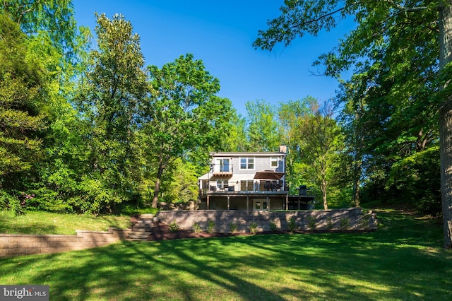 back of house featuring a chimney, a yard, and a deck