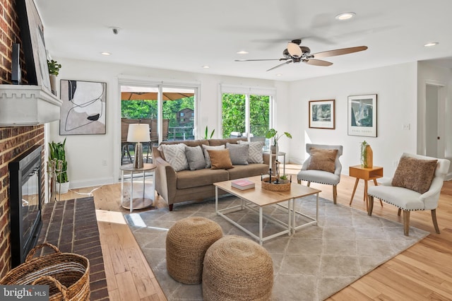 living area featuring a brick fireplace, wood finished floors, baseboards, ceiling fan, and recessed lighting