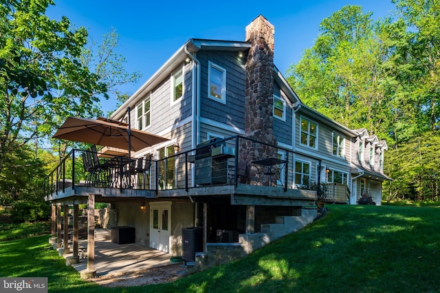 back of property featuring a patio area, a wooden deck, a yard, and a chimney