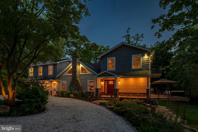 view of front of home featuring a wooden deck and gravel driveway