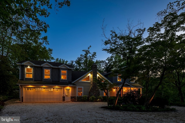 view of front of property featuring a garage, a chimney, and gravel driveway