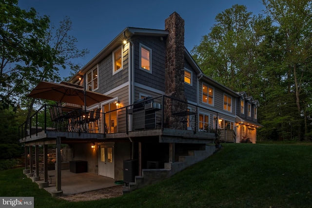 back of house with a lawn, a deck, a chimney, and a patio area