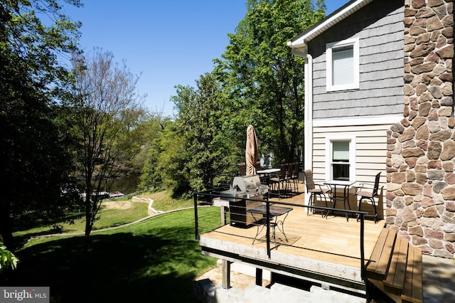 wooden deck with a lawn and outdoor dining area