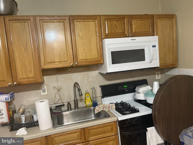 404 N 52nd St, Philadelphia, PA 19139 - kitchen featuring light countertops, a sink, white microwave, range with gas stovetop, and tasteful backsplash