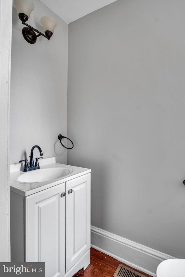 bathroom with baseboards, visible vents, wood finished floors, and vanity