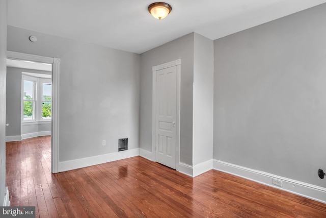 spare room with visible vents, baseboards, and hardwood / wood-style flooring
