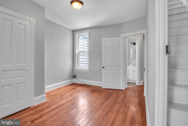 unfurnished bedroom featuring baseboards, light wood finished floors, and a closet