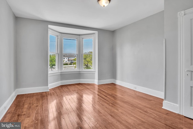 spare room featuring wood-type flooring and baseboards