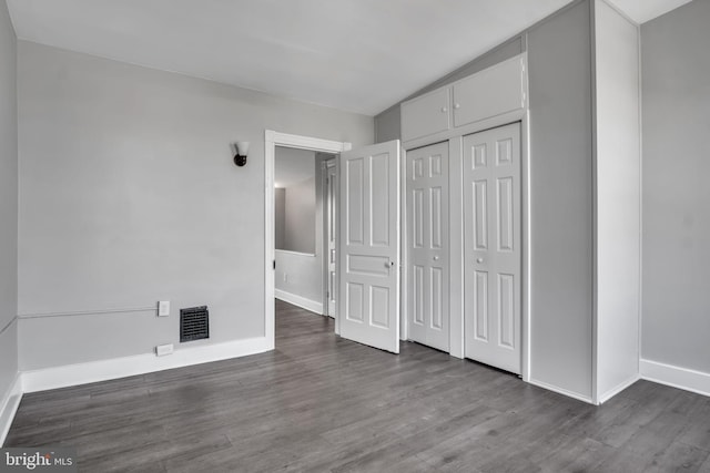 unfurnished bedroom featuring baseboards, visible vents, wood finished floors, and a closet
