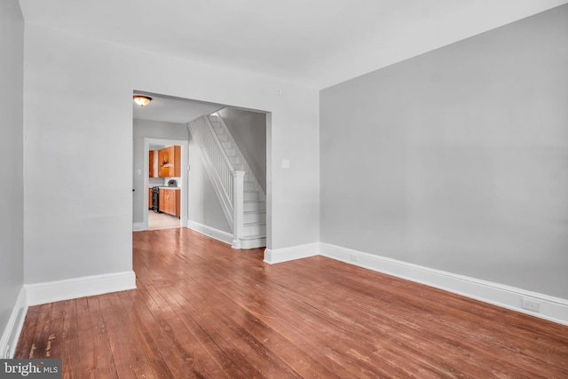 spare room featuring stairs, baseboards, and hardwood / wood-style floors