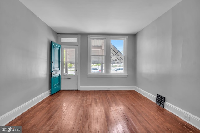 empty room with visible vents, baseboards, dark wood-type flooring, and a healthy amount of sunlight