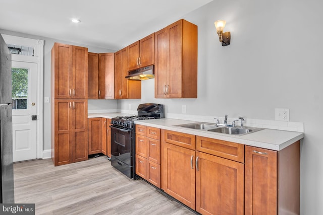 kitchen featuring a sink, light countertops, black range with gas cooktop, light wood-type flooring, and under cabinet range hood
