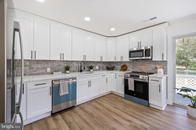2475 W Denneys Rd, Dover, DE 19904 - kitchen featuring a sink, stainless steel appliances, white cabinetry, light stone countertops, and visible vents