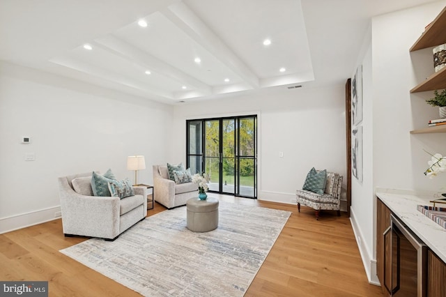 living room with recessed lighting, light wood-style floors, baseboards, and a tray ceiling