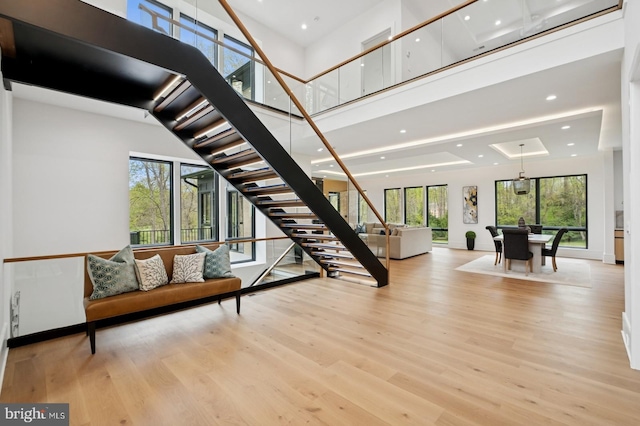 staircase with a high ceiling, a healthy amount of sunlight, wood finished floors, and recessed lighting