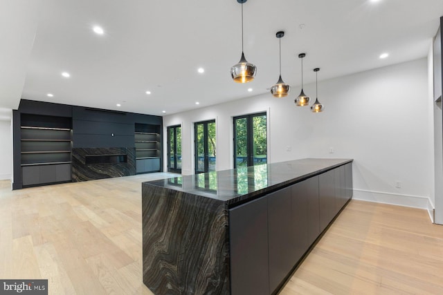 kitchen with recessed lighting, modern cabinets, a premium fireplace, light wood-type flooring, and baseboards