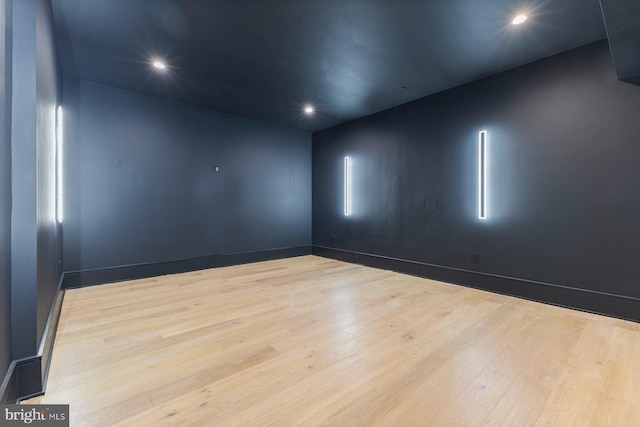 empty room with baseboards, wood finished floors, and recessed lighting