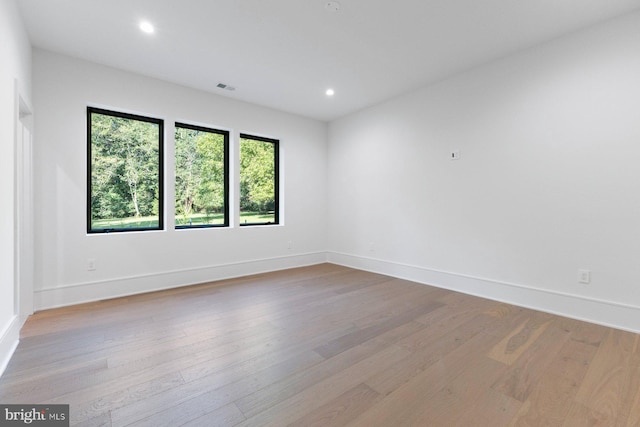 unfurnished room with recessed lighting, light wood-style flooring, visible vents, and baseboards