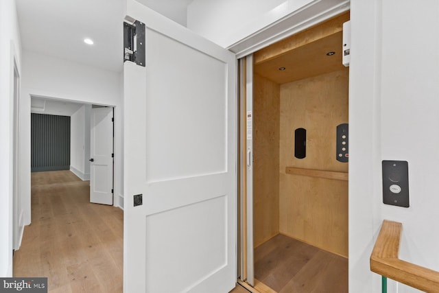 hallway with light wood-style flooring, elevator, and recessed lighting