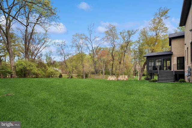 view of yard featuring a wooden deck, a sunroom, and stairway