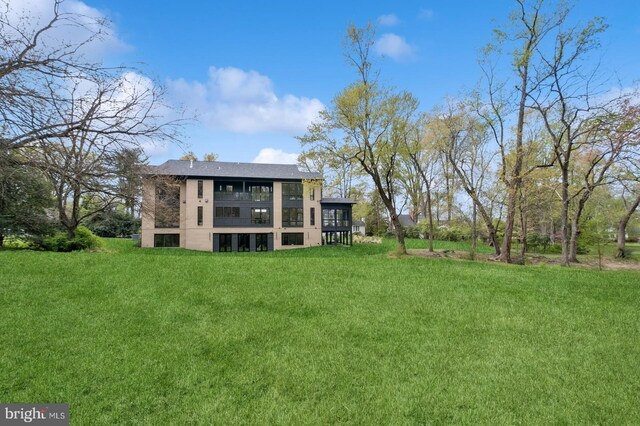 rear view of property with a yard and a balcony