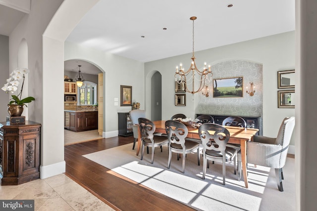 840 Childs Point Rd, Annapolis, MD 21401 - dining room with arched walkways, baseboards, a notable chandelier, and wood finished floors