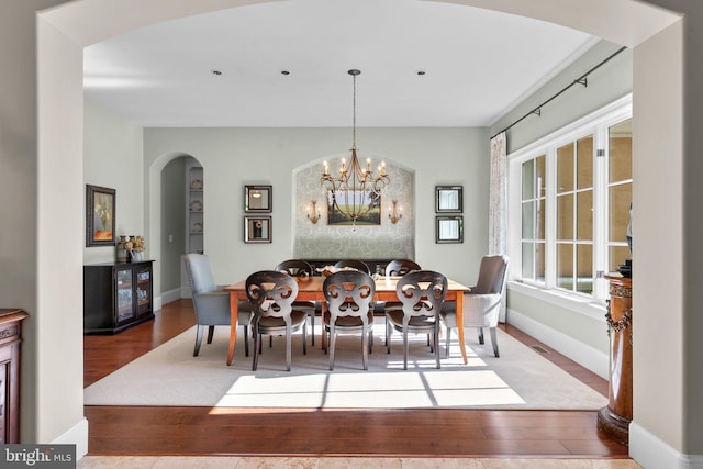 840 Childs Point Rd, Annapolis, MD 21401 - dining area with arched walkways, baseboards, an inviting chandelier, and wood finished floors