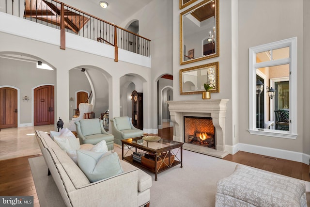 840 Childs Point Rd, Annapolis, MD 21401 - living area featuring wood finished floors, baseboards, a high ceiling, a warm lit fireplace, and arched walkways