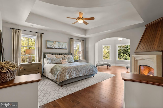840 Childs Point Rd, Annapolis, MD 21401 - bedroom featuring wood-type flooring, visible vents, a lit fireplace, a tray ceiling, and a ceiling fan