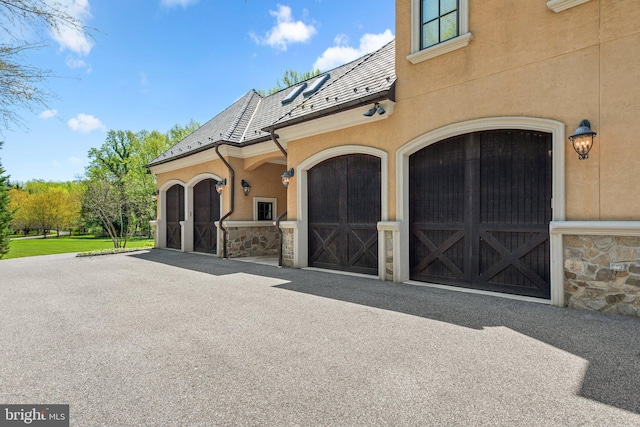840 Childs Point Rd, Annapolis, MD 21401 - exterior space featuring a high end roof, an attached garage, stone siding, stucco siding, and driveway