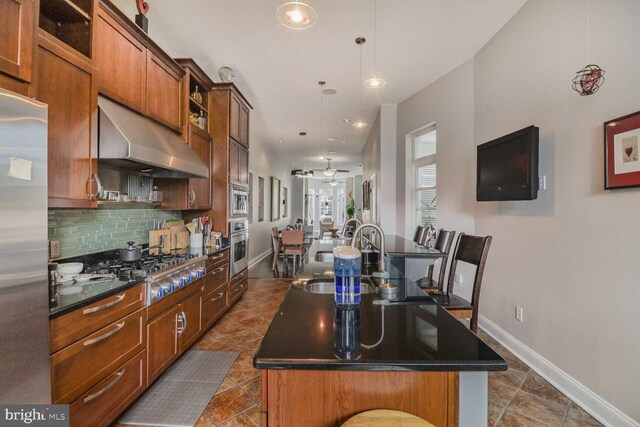 2103 Bolton St, Baltimore, MD 21217 - kitchen with under cabinet range hood, a center island with sink, and dark countertops