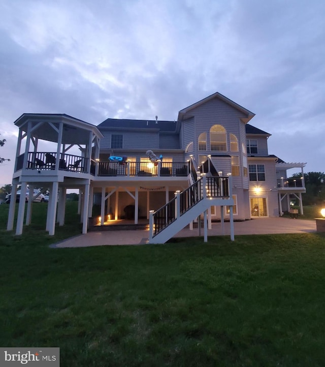 back of house with a wooden deck, a patio, and a lawn