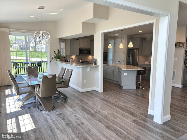dining space featuring lofted ceiling, baseboards, visible vents, a chandelier, and wood finished floors