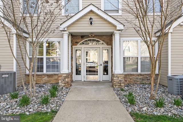 entrance to property featuring central air condition unit and stone siding