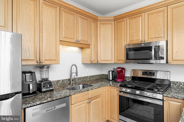 kitchen with appliances with stainless steel finishes, dark stone counters, light brown cabinets, and a sink