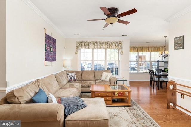 living area featuring plenty of natural light, ornamental molding, and ceiling fan with notable chandelier