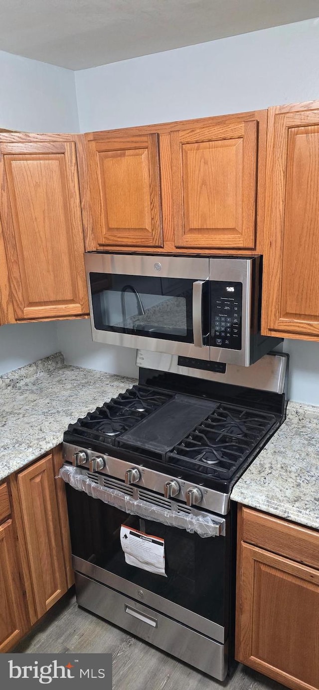 3811 Swann Rd Unit T-1, Suitland, MD 20746 - kitchen with brown cabinets, stainless steel appliances, light stone countertops, and wood finished floors