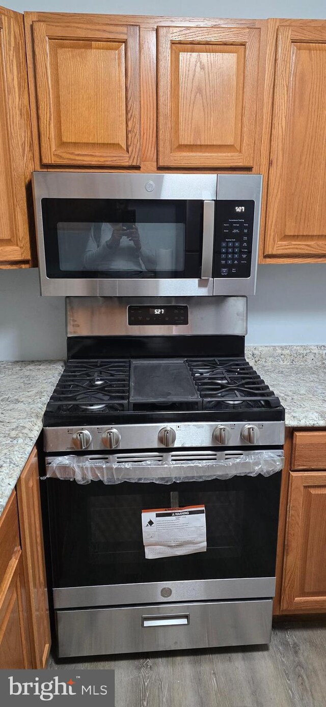 3811 Swann Rd Unit T-1, Suitland, MD 20746 - details with stainless steel appliances, light stone countertops, brown cabinetry, and wood finished floors
