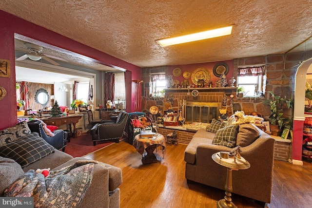1569 Prospect Ave, Willow Grove, PA 19090 - living room featuring wood finished floors, a textured ceiling, ceiling fan, arched walkways, and a fireplace