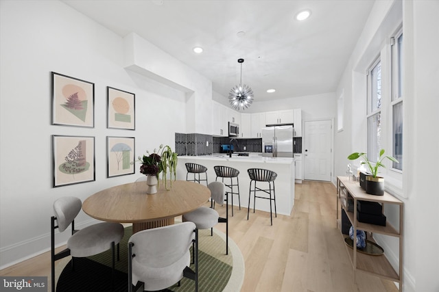 dining area featuring light wood finished floors, baseboards, and recessed lighting