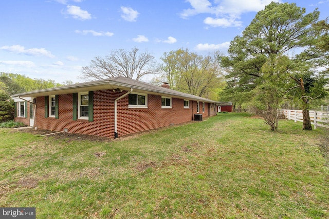 view of home's exterior featuring a chimney, fence, a yard, cooling unit, and brick siding