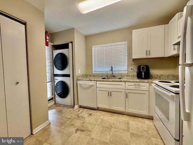 15702 Dorset Rd Unit 204, Laurel, MD 20707 - kitchen with white appliances, stacked washer and clothes dryer, a sink, white cabinets, and light stone counters