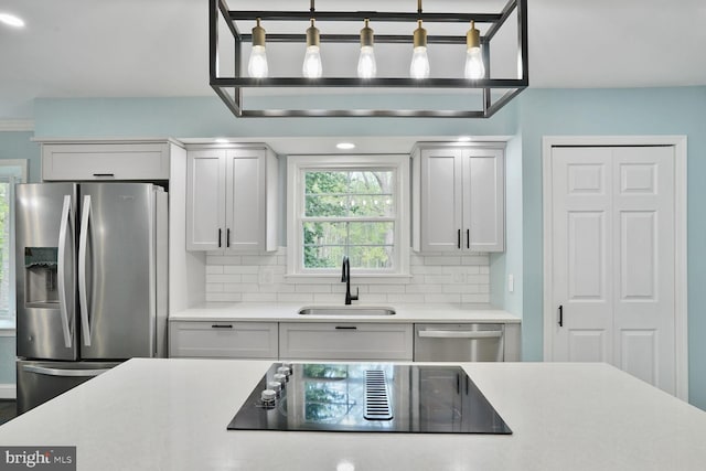 kitchen featuring tasteful backsplash, stainless steel appliances, light countertops, and a sink