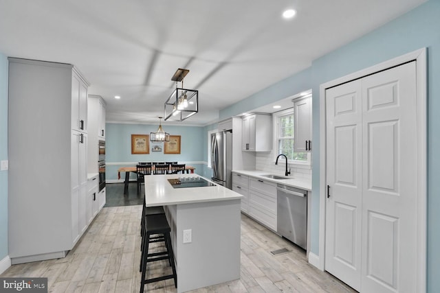 kitchen with a center island, a sink, recessed lighting, white cabinetry, and appliances with stainless steel finishes