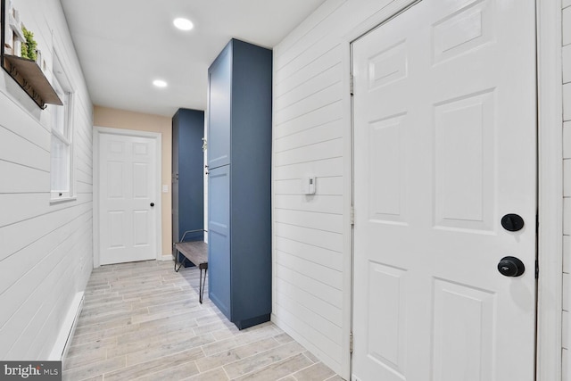 hall with recessed lighting, wooden walls, light wood-style flooring, and baseboards