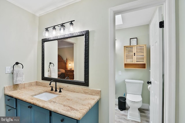 bathroom with toilet, crown molding, vanity, and wood finished floors