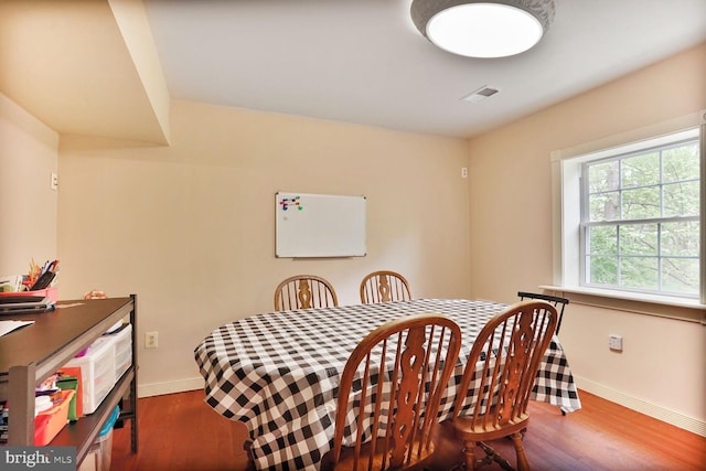 dining space with wood finished floors, visible vents, and baseboards