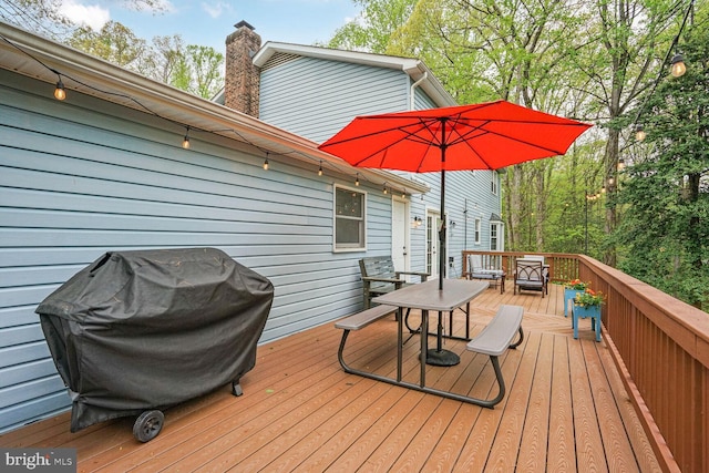 wooden deck with outdoor dining area and a grill